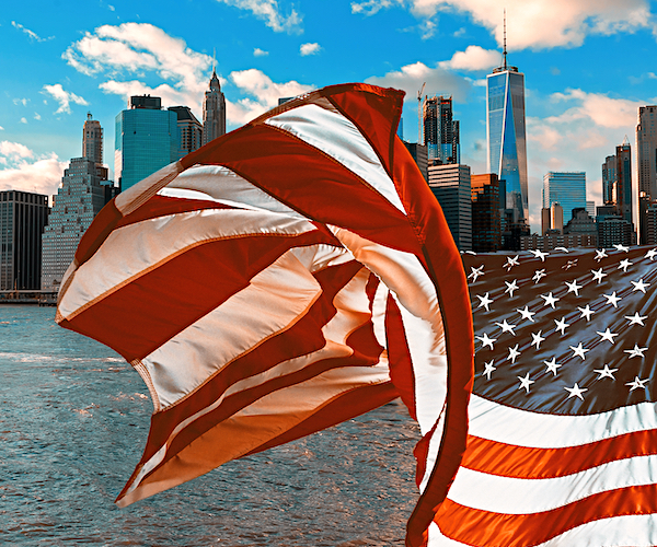 the skyline of new york city with an american flag waving in the foreground